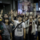 Supporters of the pro-democracy movement flash the three-finger salute from the The Hunger Games as a trailer of the movie is shown on the exterior screen of a theater in the Mongkok district of Hong Kong on November 28, 2014.